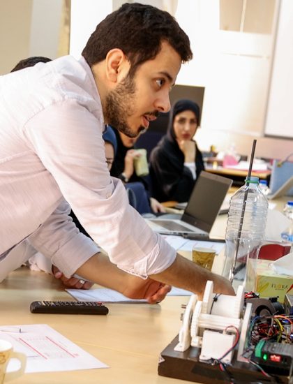 A facilitator guiding participants at an electronics workbench